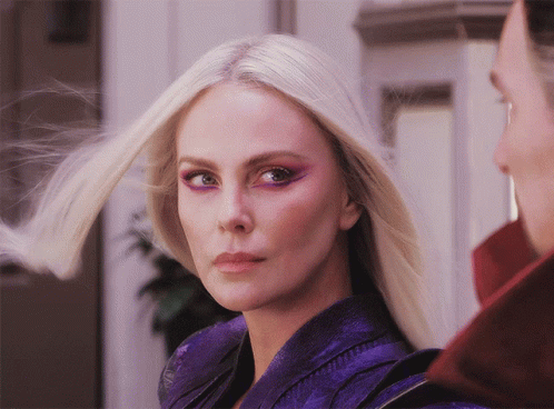 A Close Up Of A Woman 'S Face With Blonde Hair And Purple Eye Shadow GIF