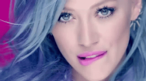 A Close Up Of A Woman 'S Face With Blue Hair And Pink Lips GIF