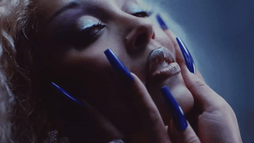 A Close Up Of A Woman 'S Face With Blue Long Nails GIF