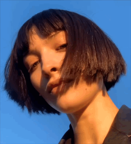 A Close Up Of A Woman 'S Face With Blue Sky In The Background GIF