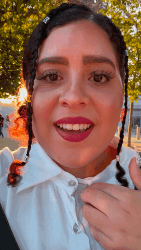 A Close Up Of A Woman 'S Face With Braids In Her Hair And A White Shirt GIF