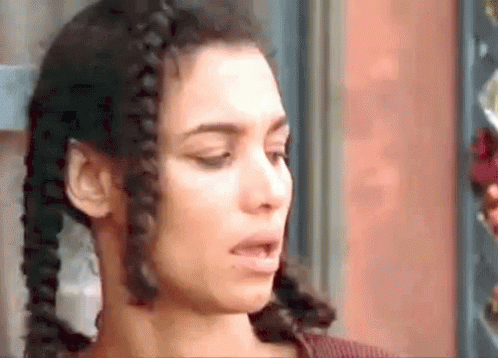 A Close Up Of A Woman 'S Face With Braids In Her Hair Making A Funny Face . GIF