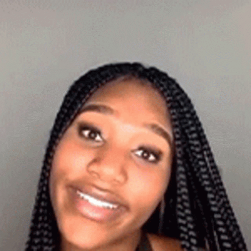 A Close Up Of A Woman 'S Face With Braids Smiling . GIF