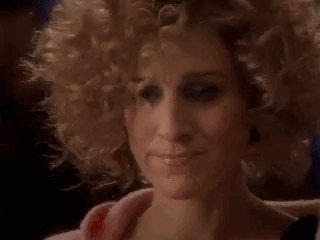 A Close Up Of A Woman 'S Face With Curly Blonde Hair . GIF