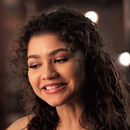 A Close Up Of A Woman 'S Face With Curly Hair . GIF