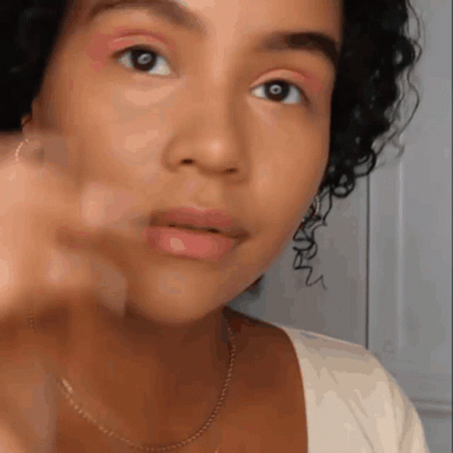 A Close Up Of A Woman 'S Face With Curly Hair And A White Shirt . GIF