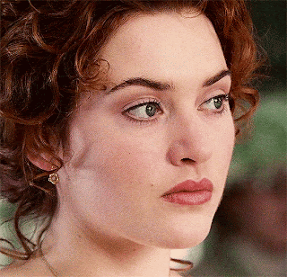 A Close Up Of A Woman 'S Face With Curly Hair And Green Eyes GIF