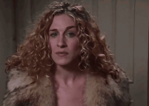A Close Up Of A Woman 'S Face With Curly Hair Wearing A Fur Coat . GIF