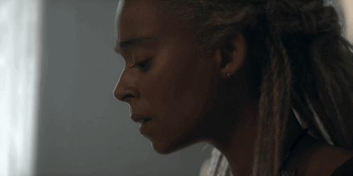 a close up of a woman 's face with dreadlocks on her hair