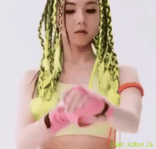 A Close Up Of A Woman 'S Face With Green And Yellow Braids And A Pink Background GIF