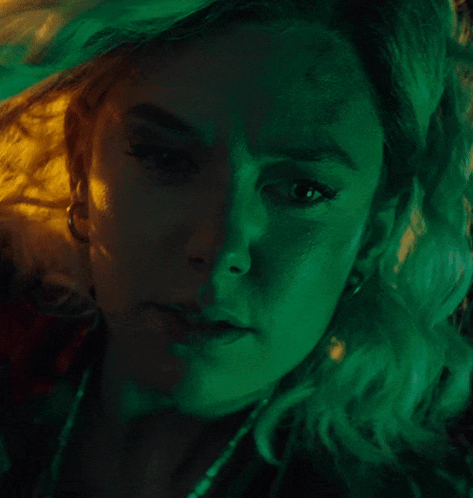 A Close Up Of A Woman 'S Face With Green And Yellow Lights Behind Her GIF
