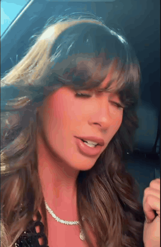 A Close Up Of A Woman 'S Face With Her Eyes Closed And A Necklace Around Her Neck . GIF