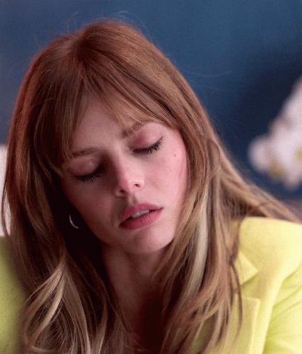 A Close Up Of A Woman 'S Face With Her Eyes Closed And A Yellow Jacket On GIF