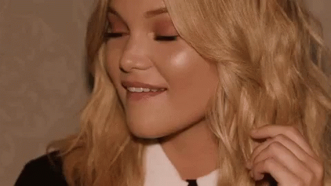 A Close Up Of A Woman 'S Face With Her Eyes Closed And Her Hair Being Touched . GIF