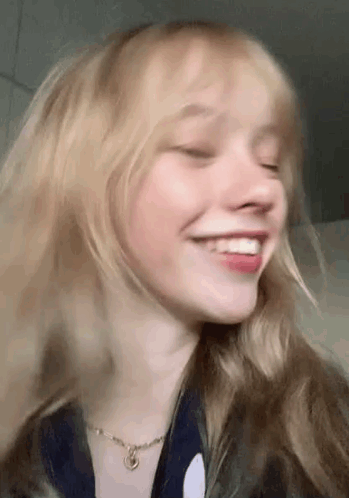 A Close Up Of A Woman 'S Face With Her Eyes Closed And Smiling . GIF
