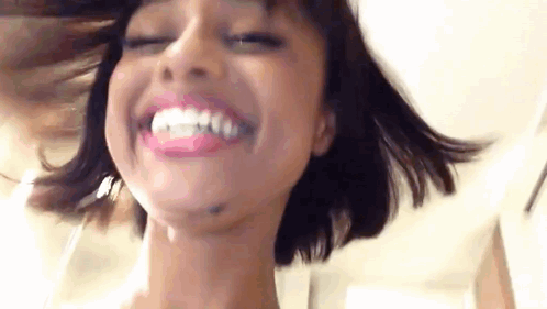 A Close Up Of A Woman 'S Face With Her Eyes Closed And Smiling . GIF