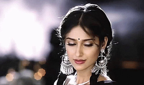 A Close Up Of A Woman 'S Face With Her Eyes Closed Wearing Earrings And A Pearl Necklace GIF