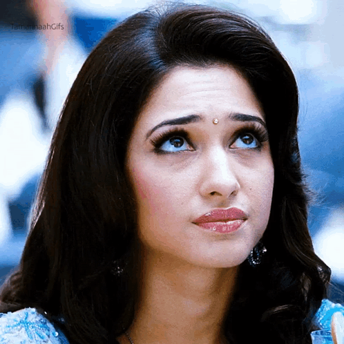 A Close Up Of A Woman 'S Face With Her Eyes Looking Up . GIF