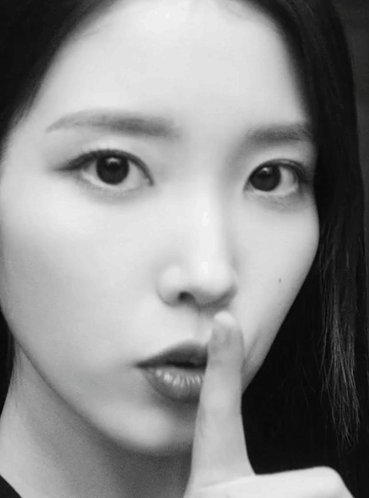 a close up of a woman 's face with her finger to her mouth
