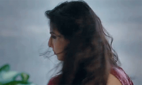 A Close Up Of A Woman 'S Face With Her Hair Blowing In The Wind GIF