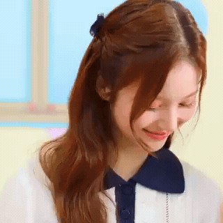 A Close Up Of A Woman 'S Face With Her Hair In A Half Up Half Down Ponytail . GIF