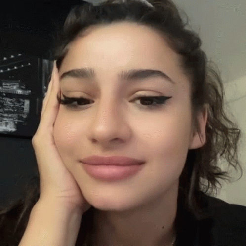 A Close Up Of A Woman 'S Face With Her Hand On Her Cheek GIF