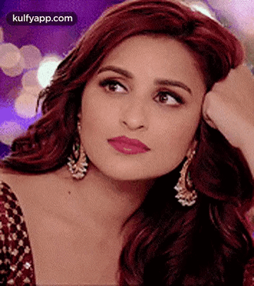 A Close Up Of A Woman 'S Face With Her Hand On Her Face And Earrings . GIF