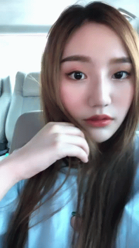 A Close Up Of A Woman 'S Face With Her Hand On Her Hair GIF