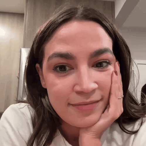 A Close Up Of A Woman 'S Face With Her Hand Resting On Her Chin GIF