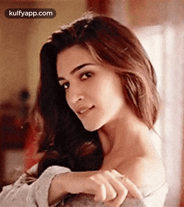 A Close Up Of A Woman 'S Face With Her Hands On Her Shoulder And Looking At The Camera . GIF