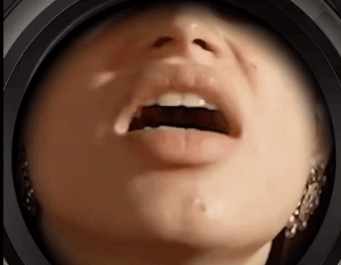 A Close Up Of A Woman 'S Face With Her Mouth Open And Earrings GIF