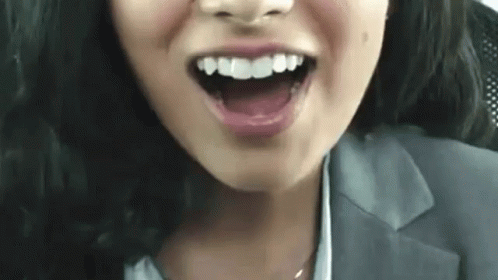 A Close Up Of A Woman 'S Face With Her Mouth Open And Her Teeth Showing . GIF