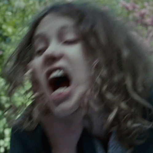 A Close Up Of A Woman 'S Face With Her Mouth Wide Open GIF