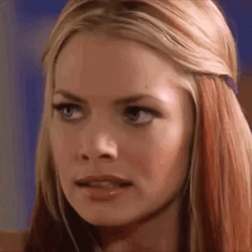 A Close Up Of A Woman 'S Face With Long Blonde Hair And Red Highlights . GIF