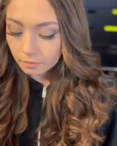 A Close Up Of A Woman 'S Face With Long Brown Hair And A Black Jacket . GIF