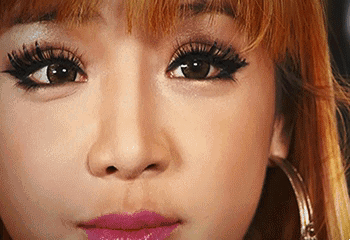 A Close Up Of A Woman 'S Face With Long Eyelashes , Pink Lips And Hoop Earrings . GIF