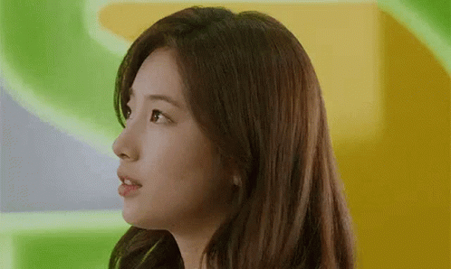 A Close Up Of A Woman 'S Face With Long Hair Against A Green And Yellow Background . GIF