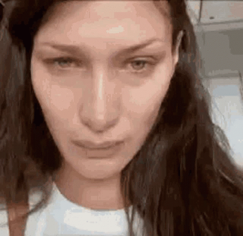 A Close Up Of A Woman 'S Face With Long Hair And A Sad Look On Her Face . GIF