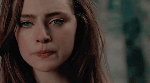 A Close Up Of A Woman 'S Face With Long Hair And Blue Eyes GIF