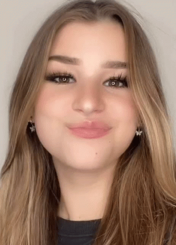 A Close Up Of A Woman 'S Face With Long Hair And Earrings GIF