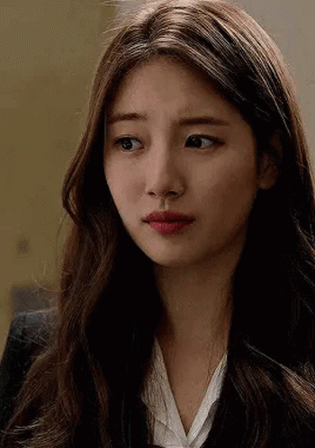 A Close Up Of A Woman 'S Face With Long Hair Wearing A Suit And White Shirt . GIF