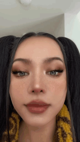 A Close Up Of A Woman 'S Face With Pigtails And Red Lips . GIF