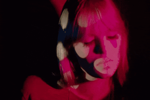 A Close Up Of A Woman 'S Face With Pink Flowers Projected On Her Face GIF