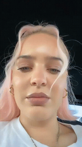 A Close Up Of A Woman 'S Face With Pink Hair And A White Shirt GIF