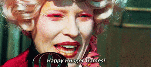 A Close Up Of A Woman 'S Face With Pink Makeup And The Words `` Happy Hunger Games ! '' GIF
