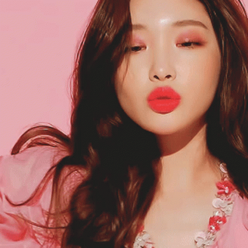 A Close Up Of A Woman 'S Face With Red Lips And A Pink Background GIF