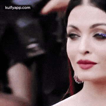 A Close Up Of A Woman 'S Face With Red Lipstick And Blue Eye Shadow . GIF