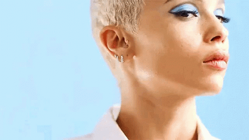 A Close Up Of A Woman 'S Face With Short Blonde Hair And Blue Eye Shadow . GIF