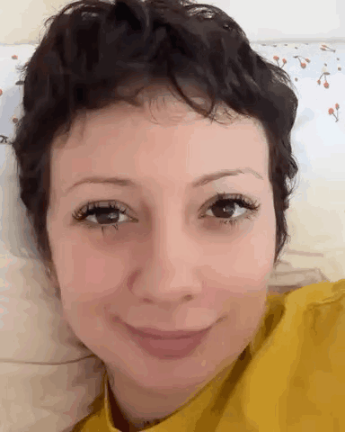 a close up of a woman 's face with short hair and a yellow shirt .