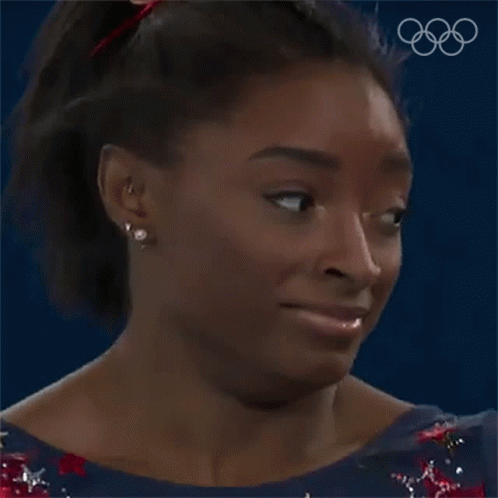 A Close Up Of A Woman 'S Face With The Olympic Rings Behind Her . GIF